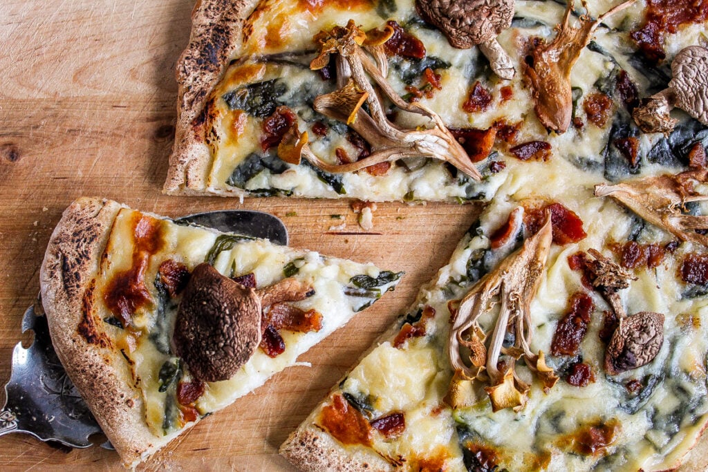 wild mushroom and ramp pizza with slice cut out.