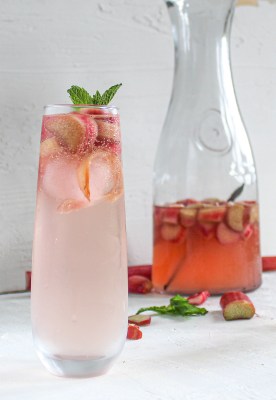 glass of pink rhubarb sangria, carafe behind