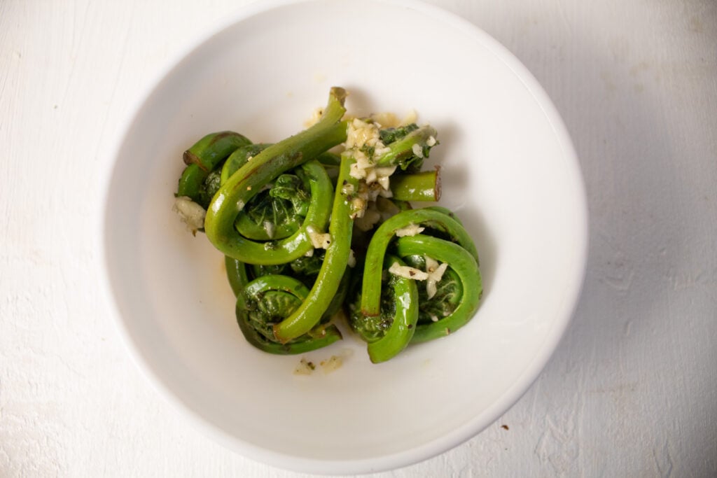 fiddlehead ferns marinating in oil and garlic.