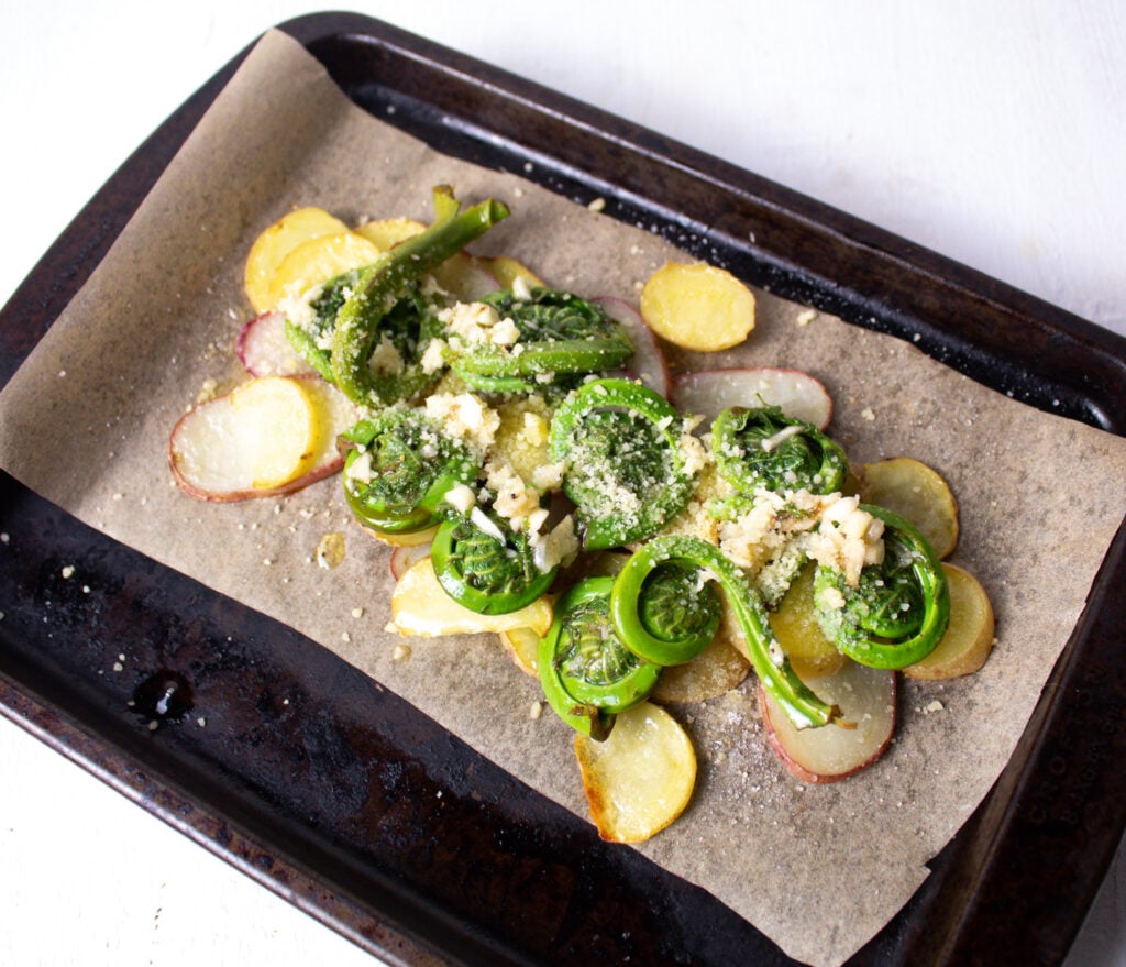 fiddlehead ferns layered over sliced potato's.