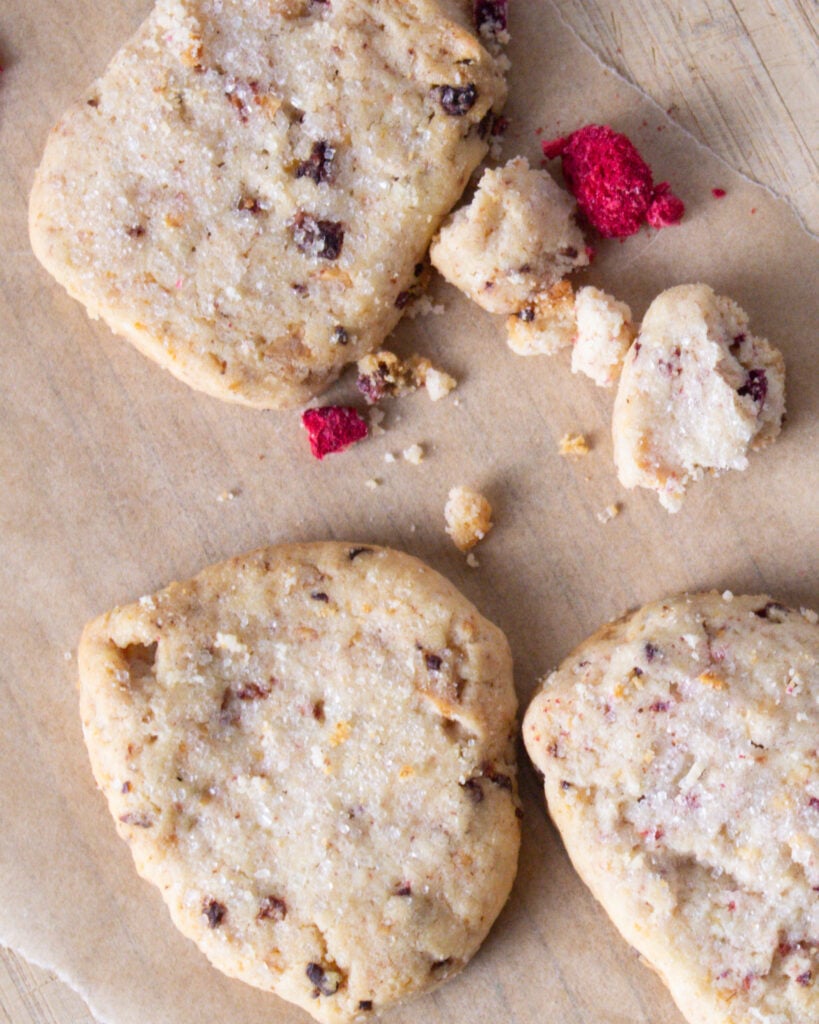 white chocolate butter cookies with raspberry and rose on cutting board.