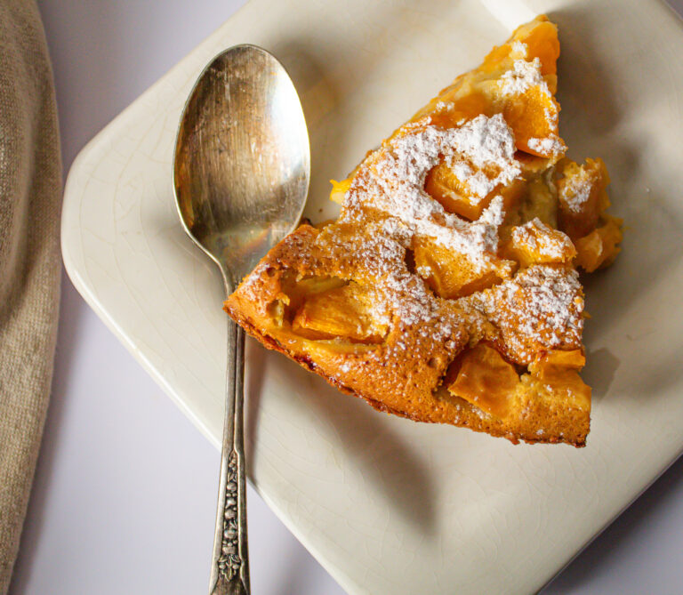 apricot and chamomile infused clafoutis with powdered sugar on plate.