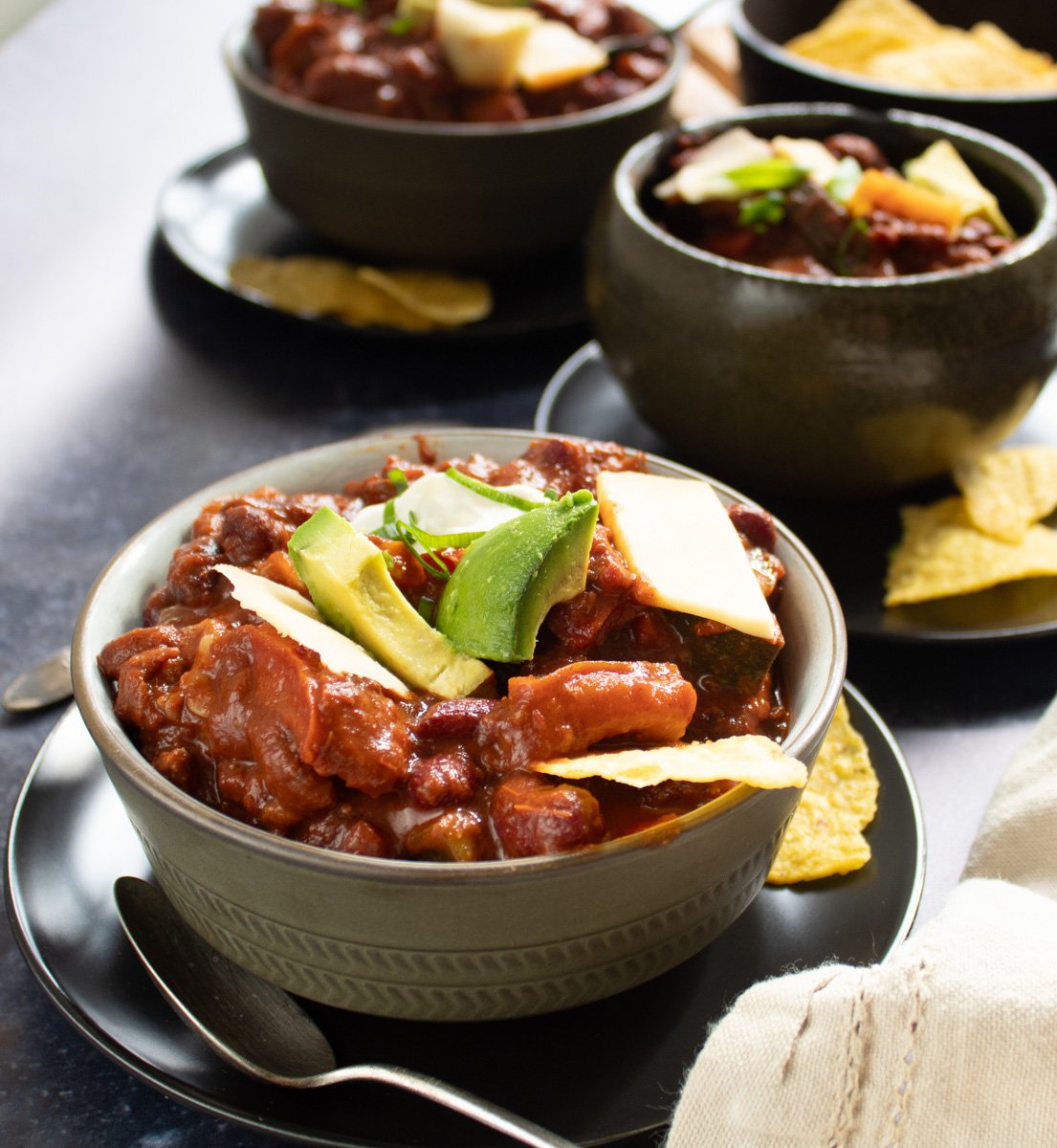 turkey chili soup in bowls with bowls behind.