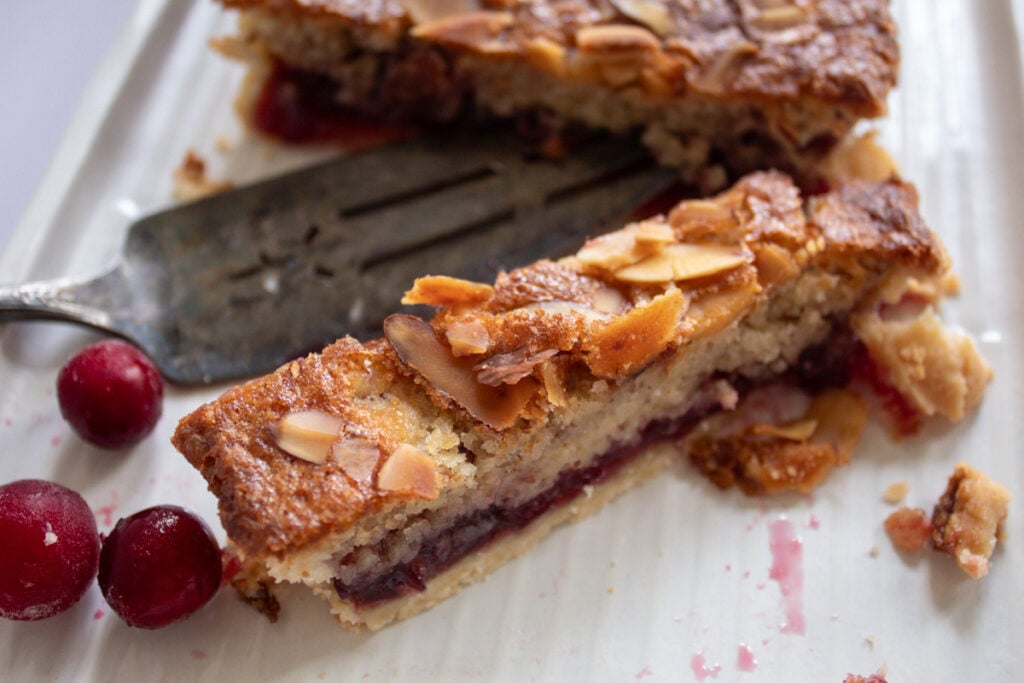 cranberry bars with fresh cranberries and serving spatula.