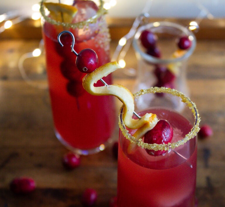 golden sugar rimmed glasses with cranberry and orange garnish.