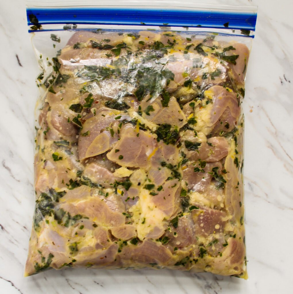 bag of chicken thighs marinating in herb rub.