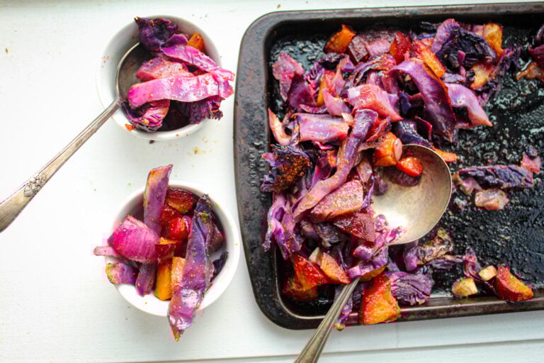 red cabbage, plums on black baking sheet.
