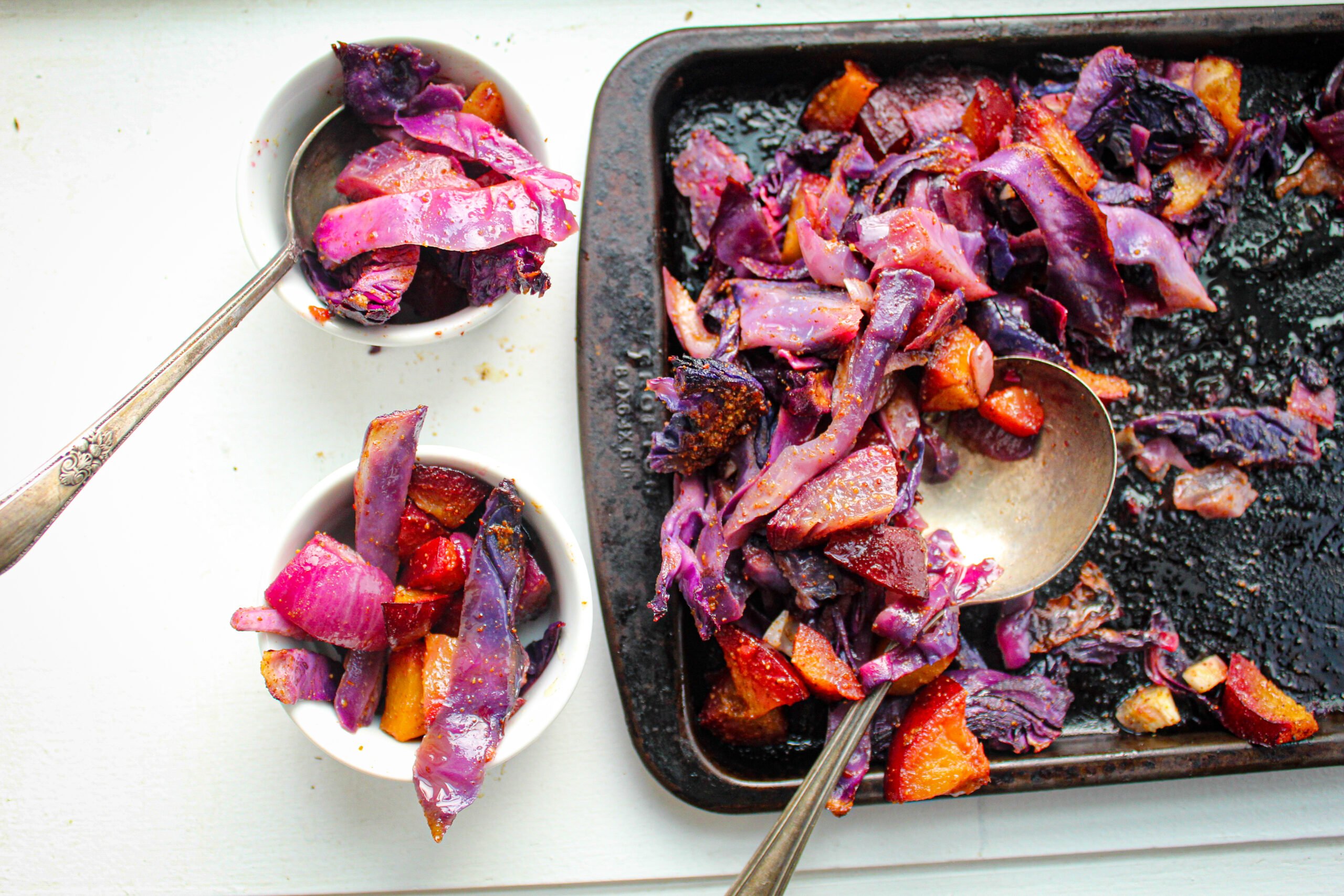 red cabbage, plums on black baking sheet.