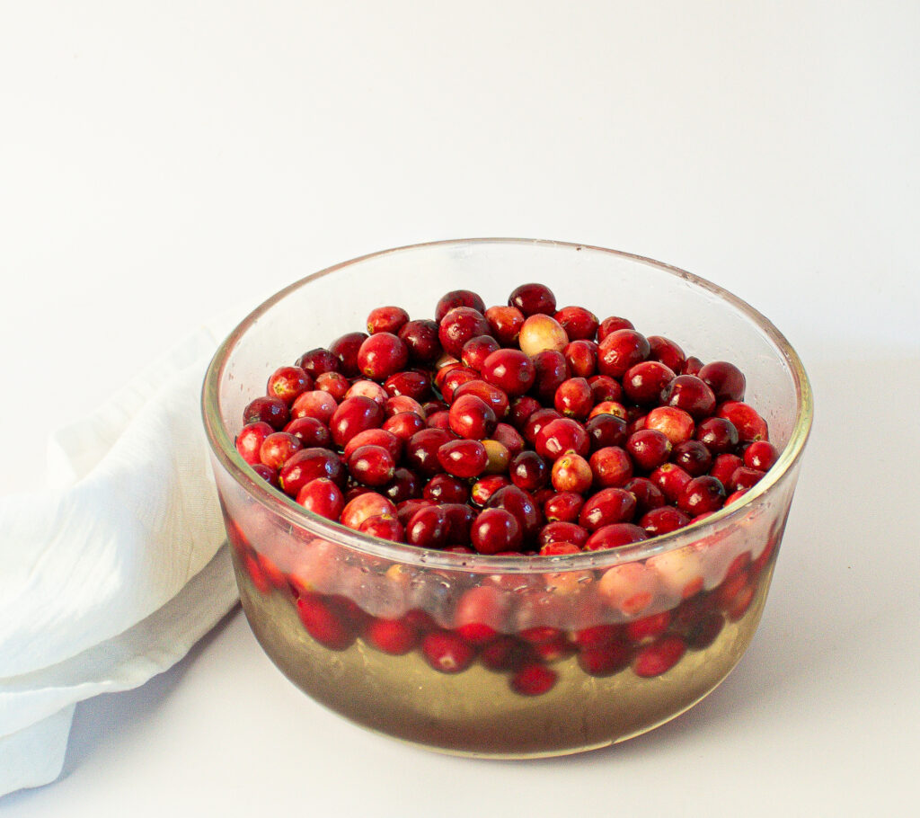 bowl of fresh cranberries soaking in sugar syrup.