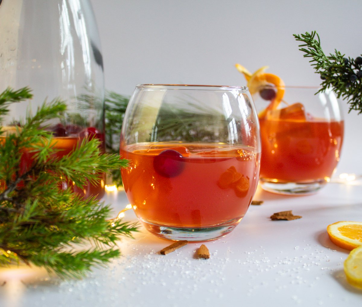 cranberry punch in glasses with orange twist garnish and evergreen boughs