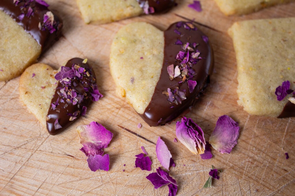 Chocolate dipped pistachio cookies garnished with crushed rose petals, 