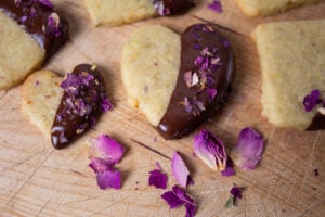 Chocolate dipped pistachio cookies garnished with crushed rose petals,