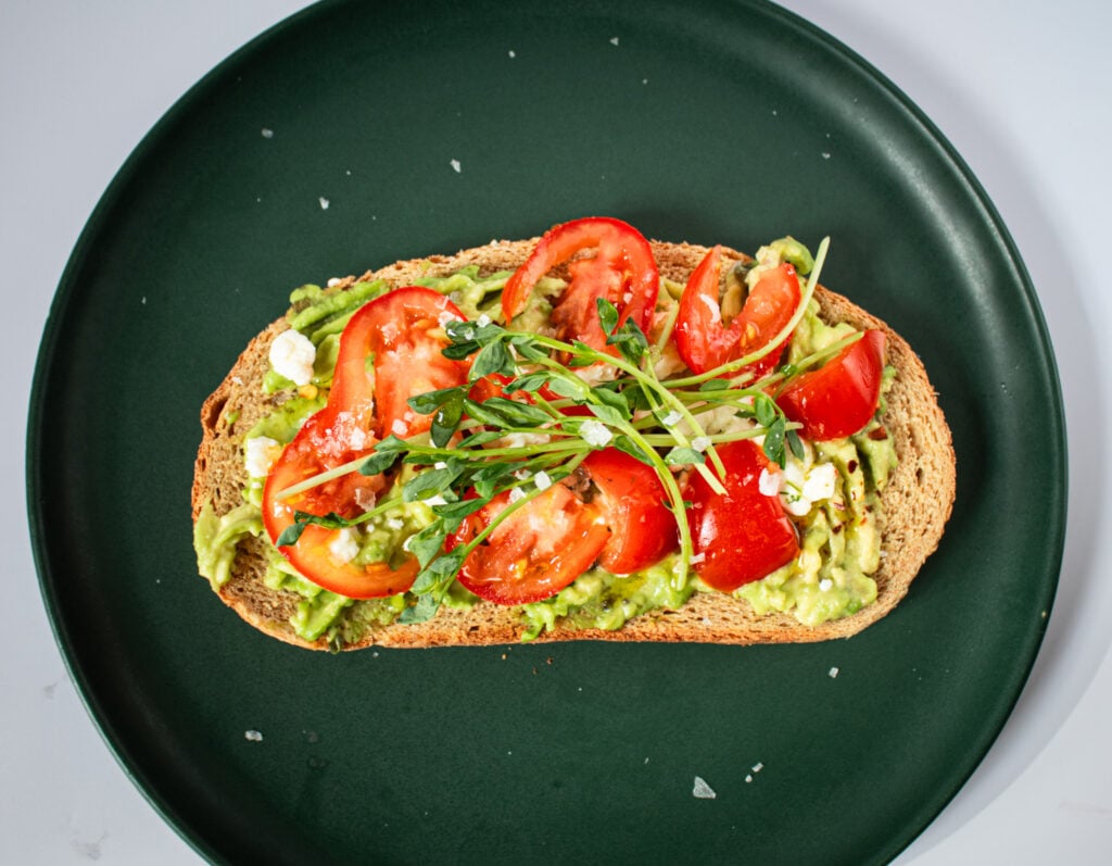 Open faced avocado toast with tomato's and pea shoot garnish.