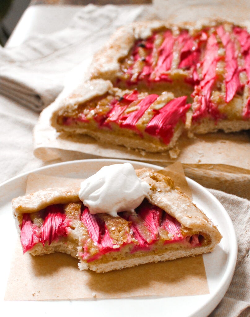 Slice of rhubarb galette with almond frangipane with whipped cream.